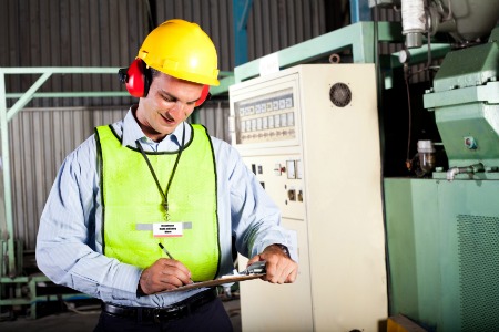 male occupational health and safety officer inside factory doing inspection