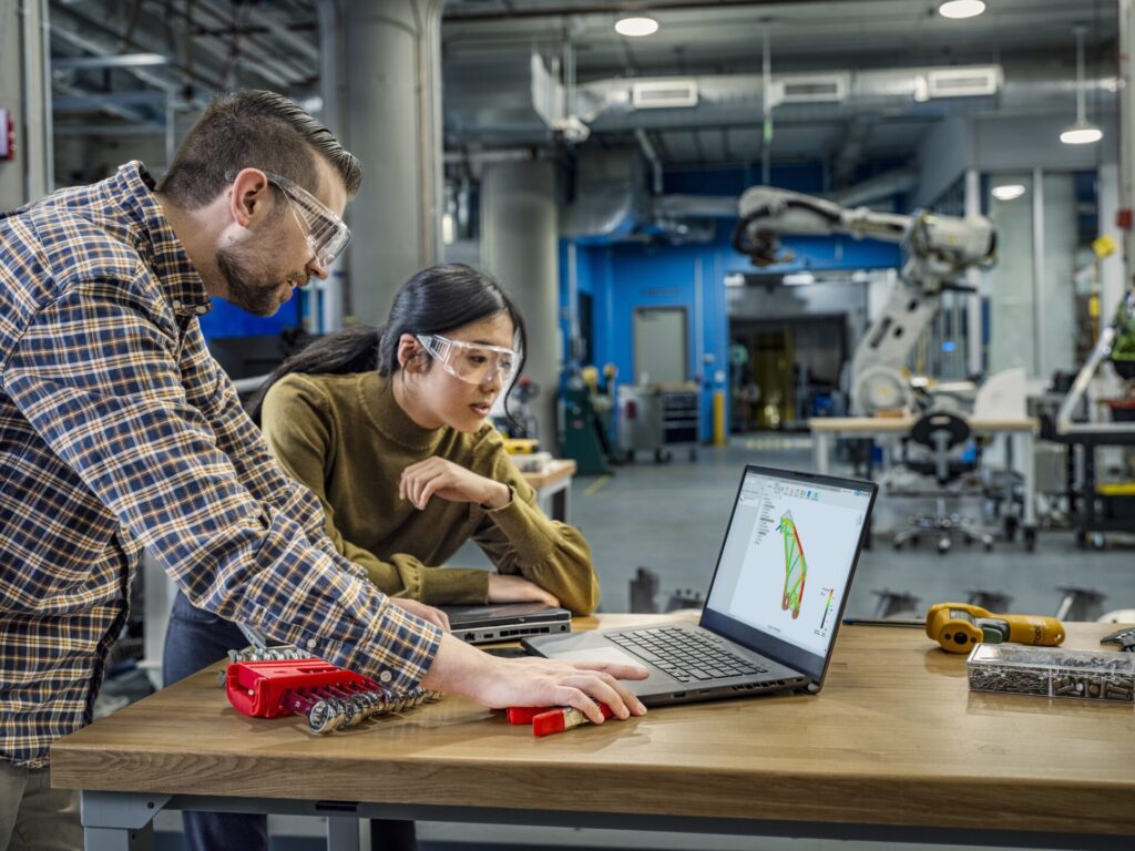 Two people collaborating using Autodesk Fusion on a laptop