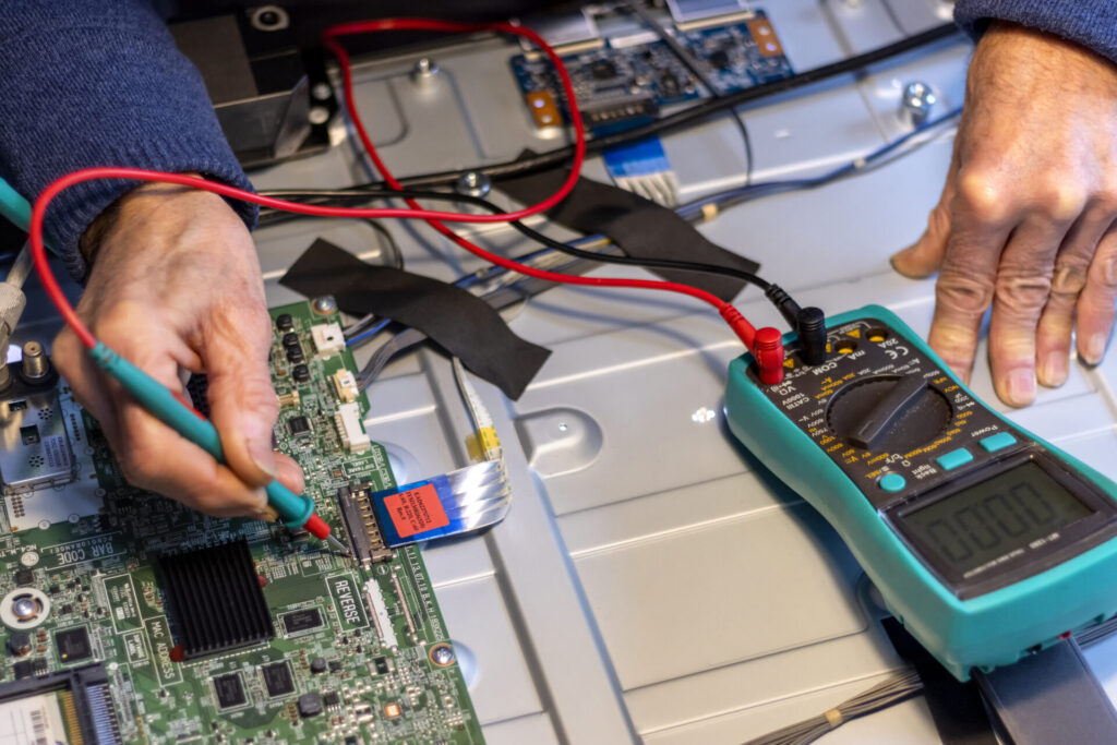 Senior electronics technician checks the components with an electrical meter